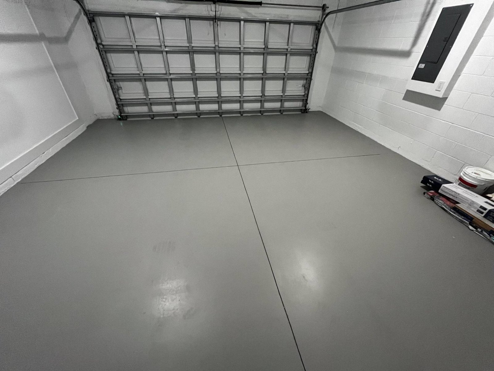 Clean garage with gray epoxy floor, white walls, and closed garage door.