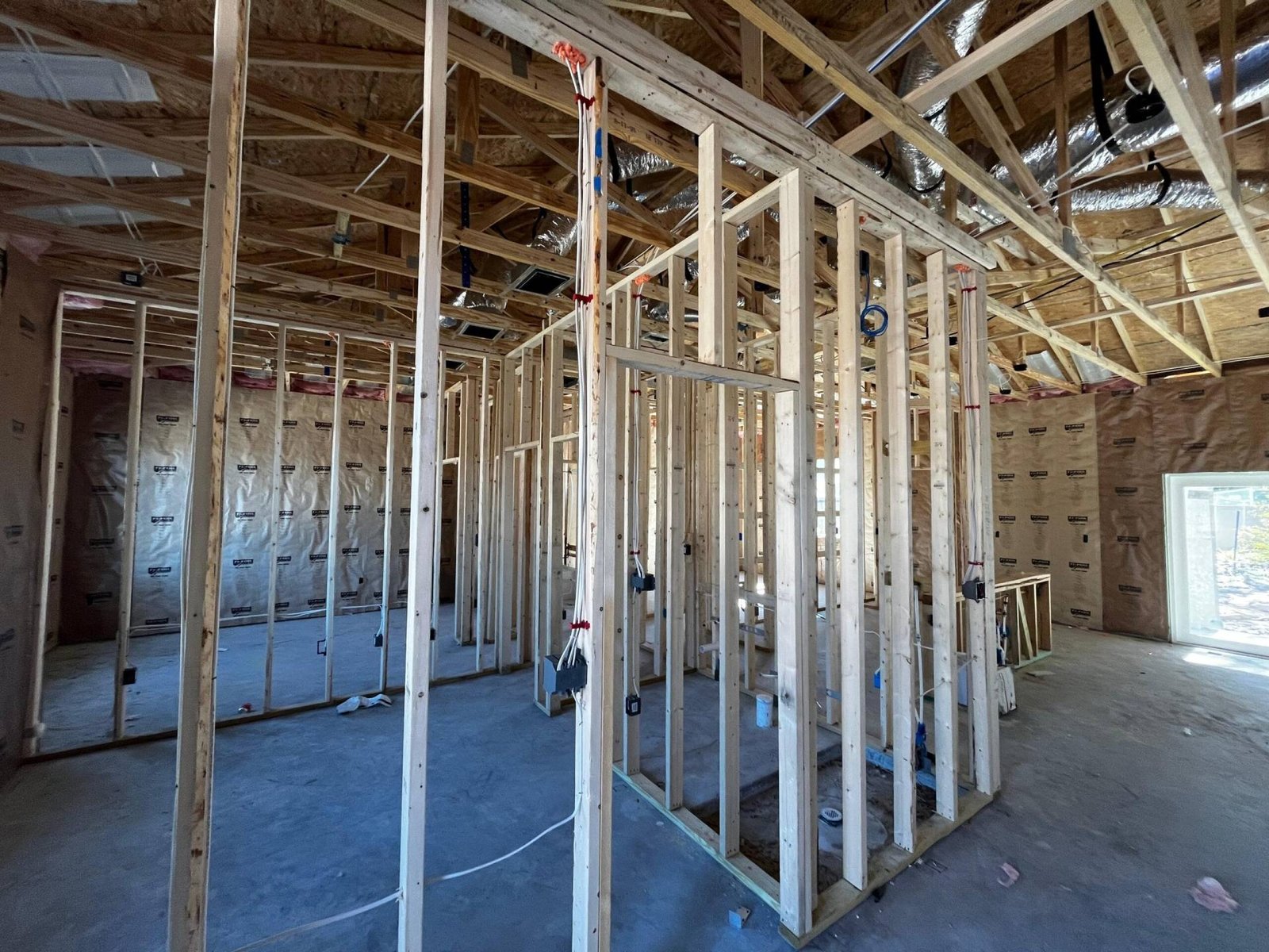 New house construction: interior framing with exposed studs, wiring, and ceiling rafters.