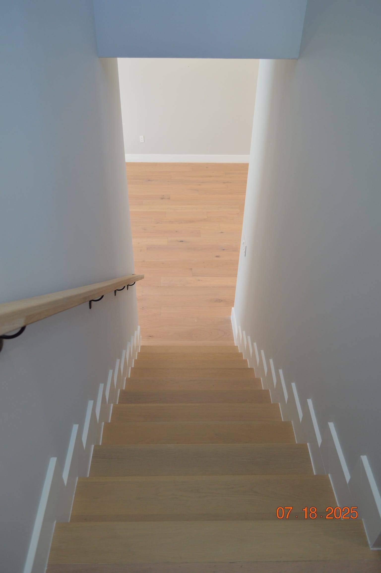 Wooden stairs leading to a bright, modern home interior.