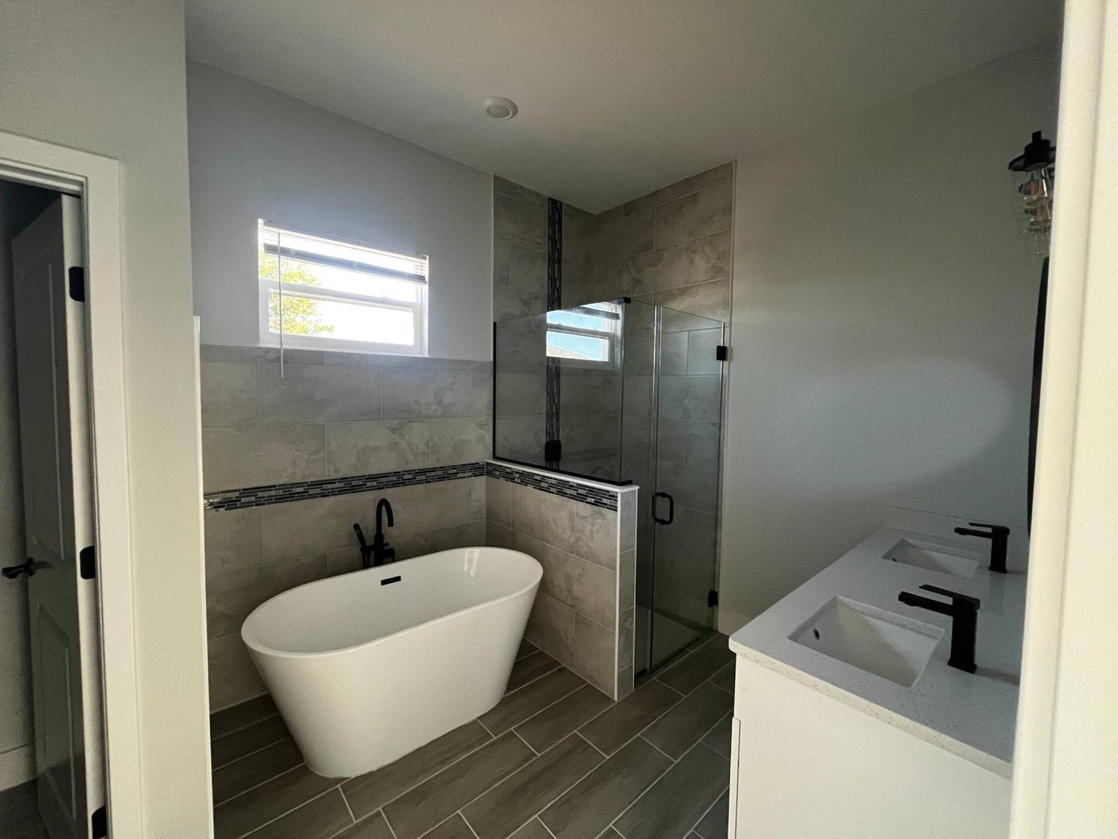 Modern bathroom with freestanding tub, glass shower, and double vanity.