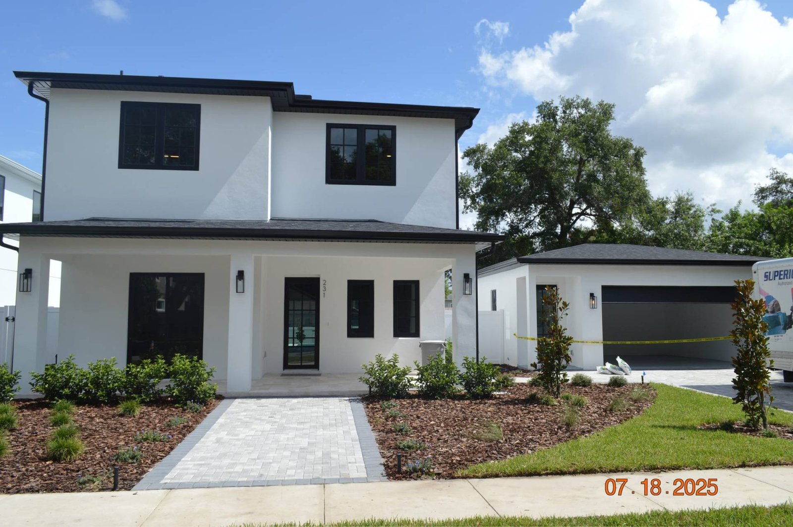 Modern white two-story home with black trim and detached garage.